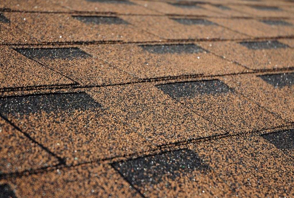 Building new house with asphalt shingle roof. Close up on brown roof shingles as a textured background