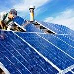 Man installing alternative energy photovoltaic solar panels on roof