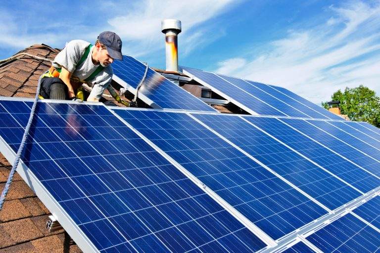 Man installing alternative energy photovoltaic solar panels on roof