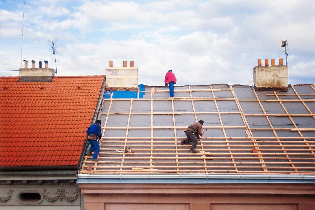 three builders replace the tiled roof in the old town