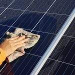 Hand cleaning solar panels. A woman’s hands use a towel to wipe