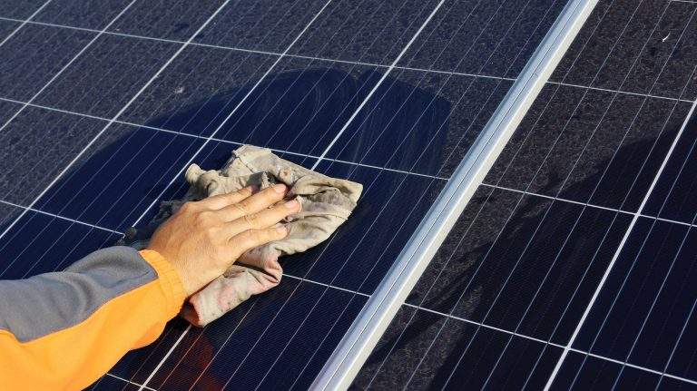 Hand cleaning solar panels. A woman’s hands use a towel to wipe
