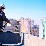 Roofer installing roofing felt by means of gas blowpipe torch